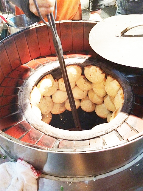 台北饒河夜市の胡椒餅やさん。釜の縁に故障餅をひっつけて焼いていきます。